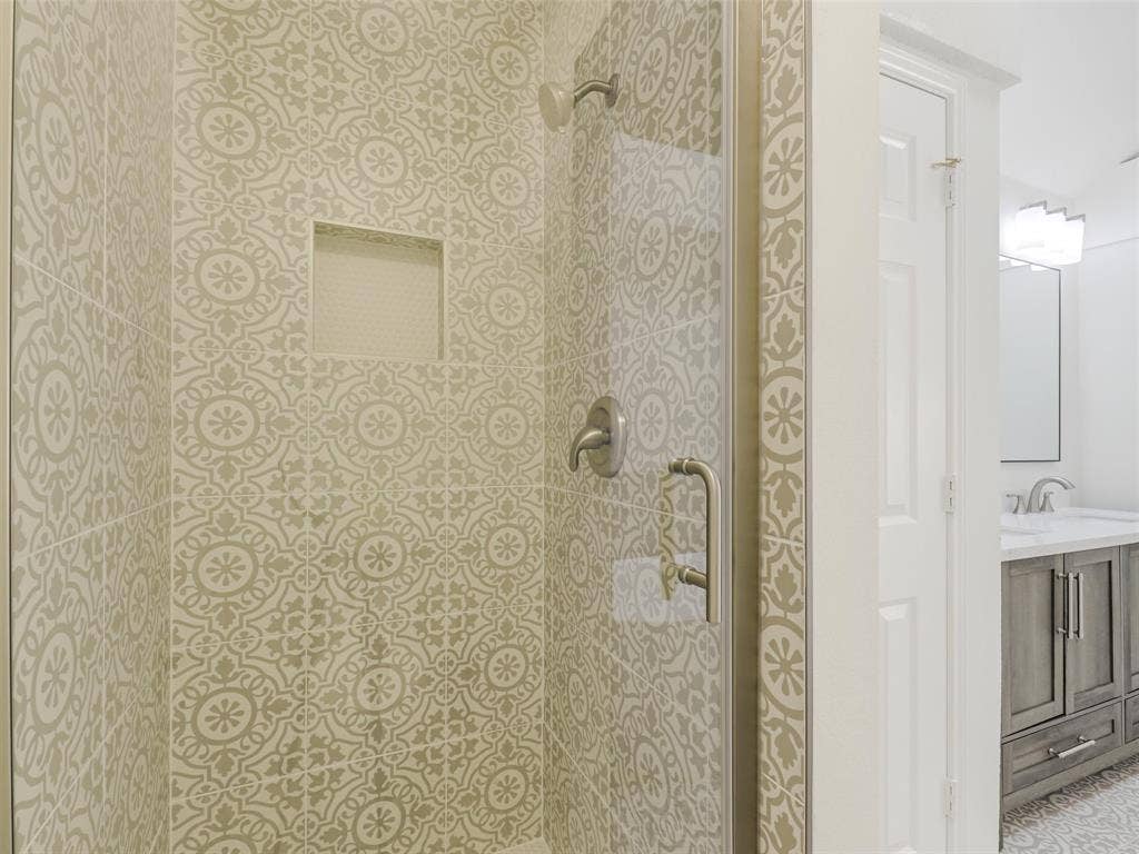 2327 N Ridge Road, McKinney, TX 75072 Patterned shower tile, built-in shower niche, brushed nickel fixtures, glass shower enclosure, and a vanity with a light-colored countertop