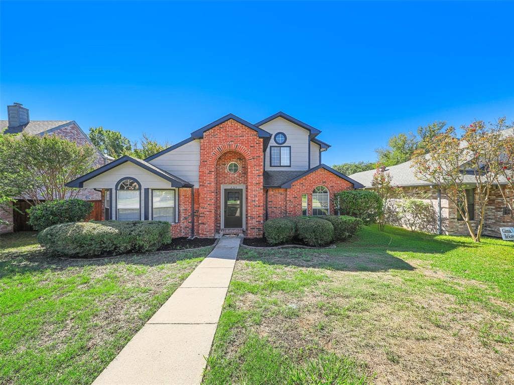 2327 N Ridge Road, McKinney, TX 75072 Red brick facade with arched entryway, light gray siding accents, and gabled roofline