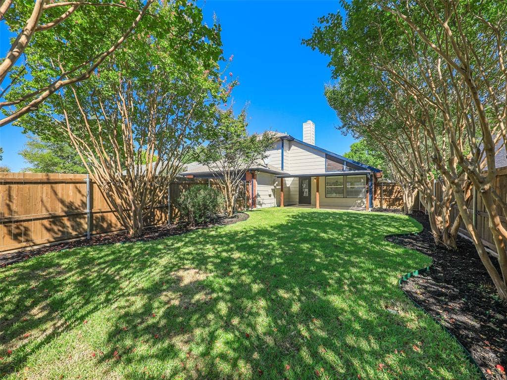 2327 N Ridge Road, McKinney, TX 75072 Expansive lawn with mature trees, a covered patio, and wood privacy fencing