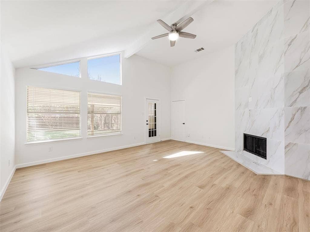 2327 N Ridge Road, McKinney, TX 75072 Vaulted ceiling with exposed beam, wood-finish flooring, white marble-look fireplace, large picture windows, and a ceiling fan