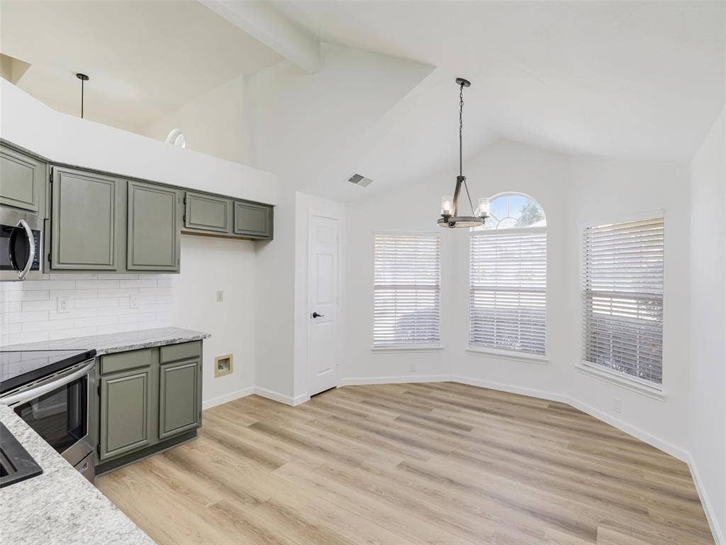 2327 N Ridge Road, McKinney, TX 75072 Vaulted ceiling, wood-finish flooring, gray cabinetry, granite-style countertops, and a subway tile backsplash