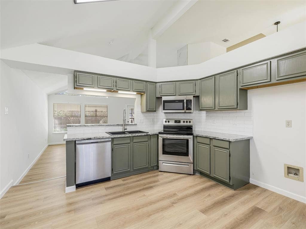 2327 N Ridge Road, McKinney, TX 75072 Kitchen featuring wood-finish flooring, stainless steel appliances, grey cabinetry, white subway tile backsplash, and light-toned countertops