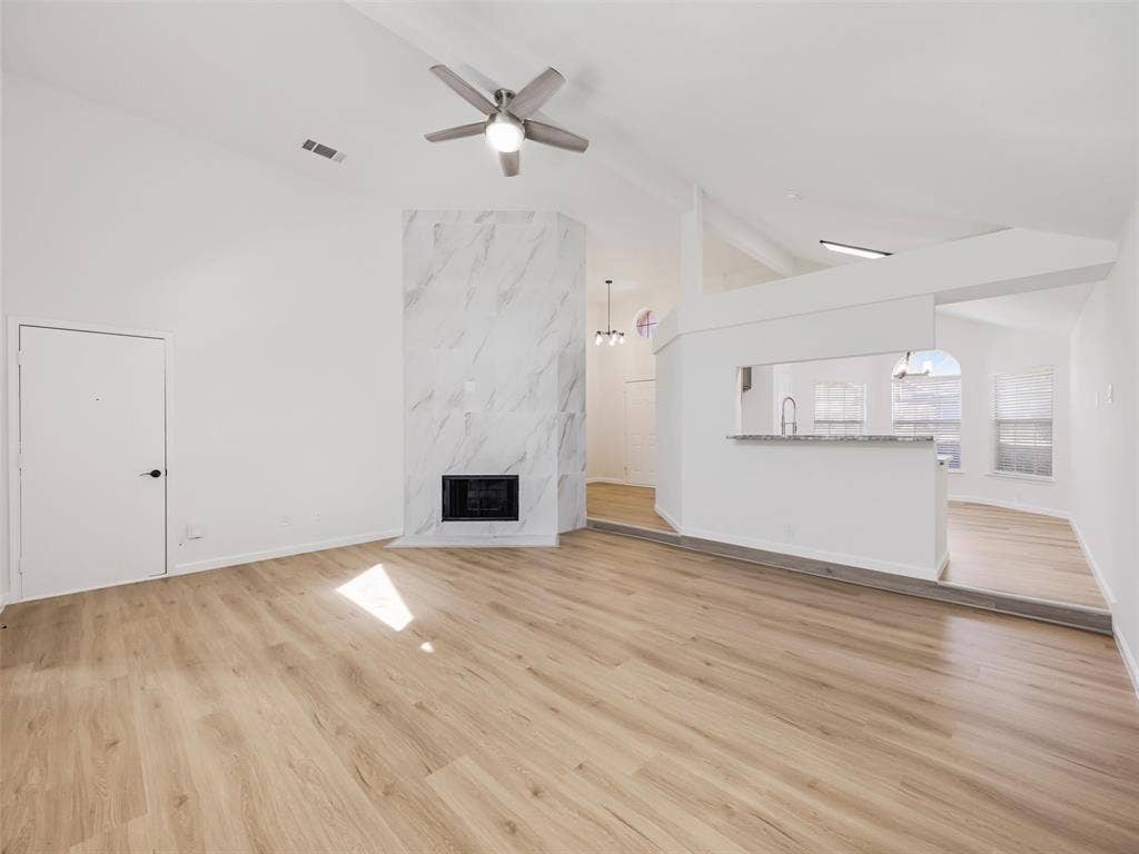 2327 N Ridge Road, McKinney, TX 75072 Vaulted ceilings with a ceiling fan, fireplace with a marble-finish surround, wood-finish flooring, and a breakfast bar with a stone-finish countertop