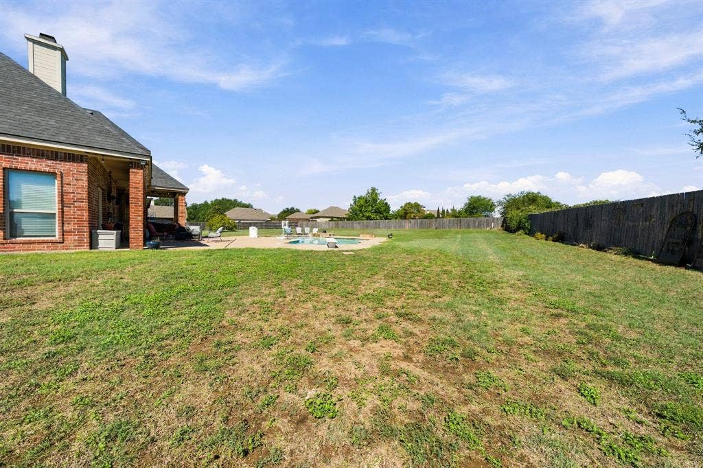1021 Cascade Trail, McGregor, TX 76657 Brick exterior with a covered patio, adjacent to a perimeter wooden fence