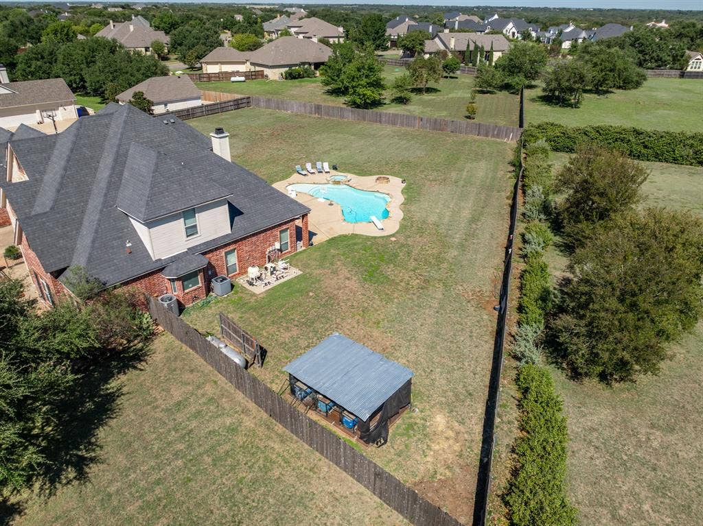 1021 Cascade Trail, McGregor, TX 76657 Brick exterior with a dark shingle roof and multiple chimneys