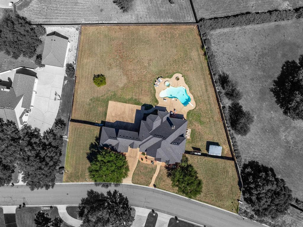 1021 Cascade Trail, McGregor, TX 76657 Spacious property featuring a multi-gabled roofline, an irregular-shaped pool with integrated spa, an expansive paved patio, and a dedicated storage shed
