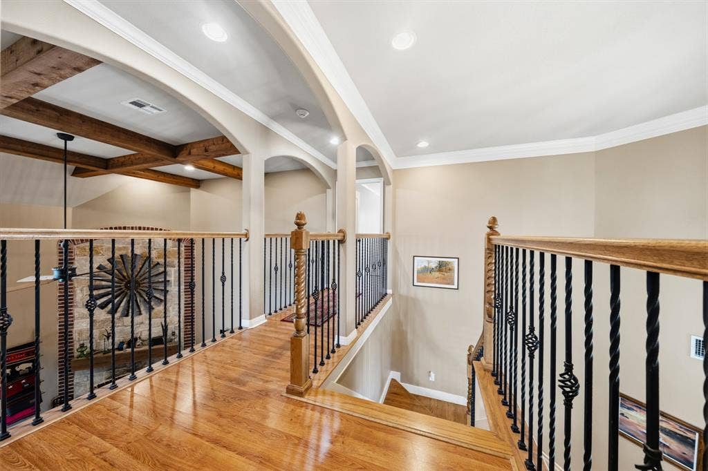 1021 Cascade Trail, McGregor, TX 76657 Wood-finish flooring, wrought iron balusters with wood handrails, recessed lighting, arched doorways, and exposed wood beams