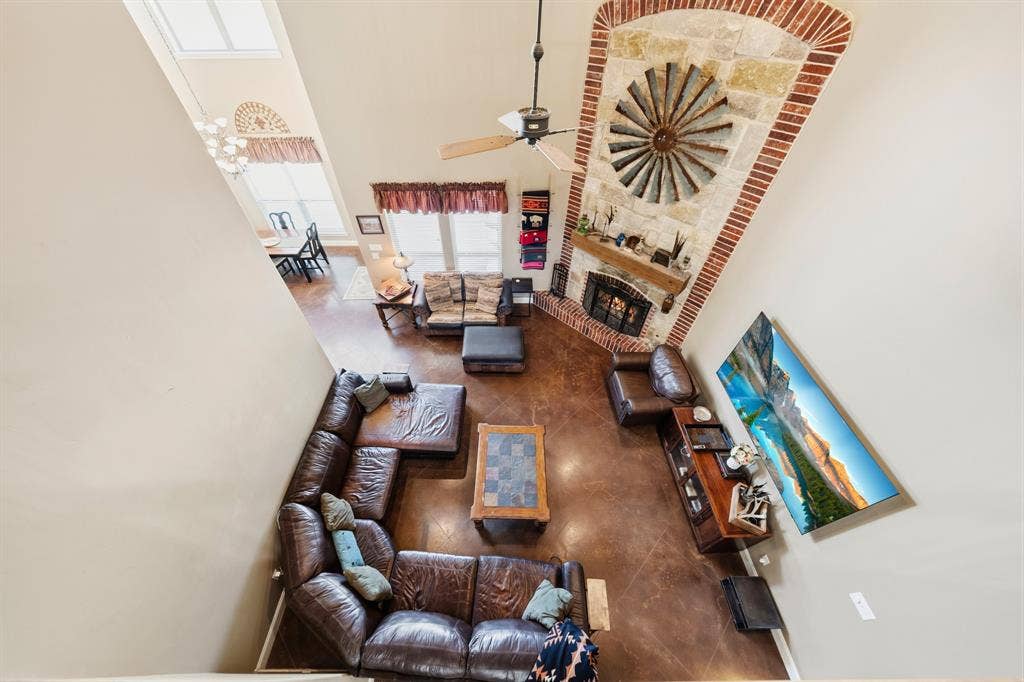 1021 Cascade Trail, McGregor, TX 76657 Two-story living area featuring a stone and brick fireplace, ceiling fan, and wood-finish flooring