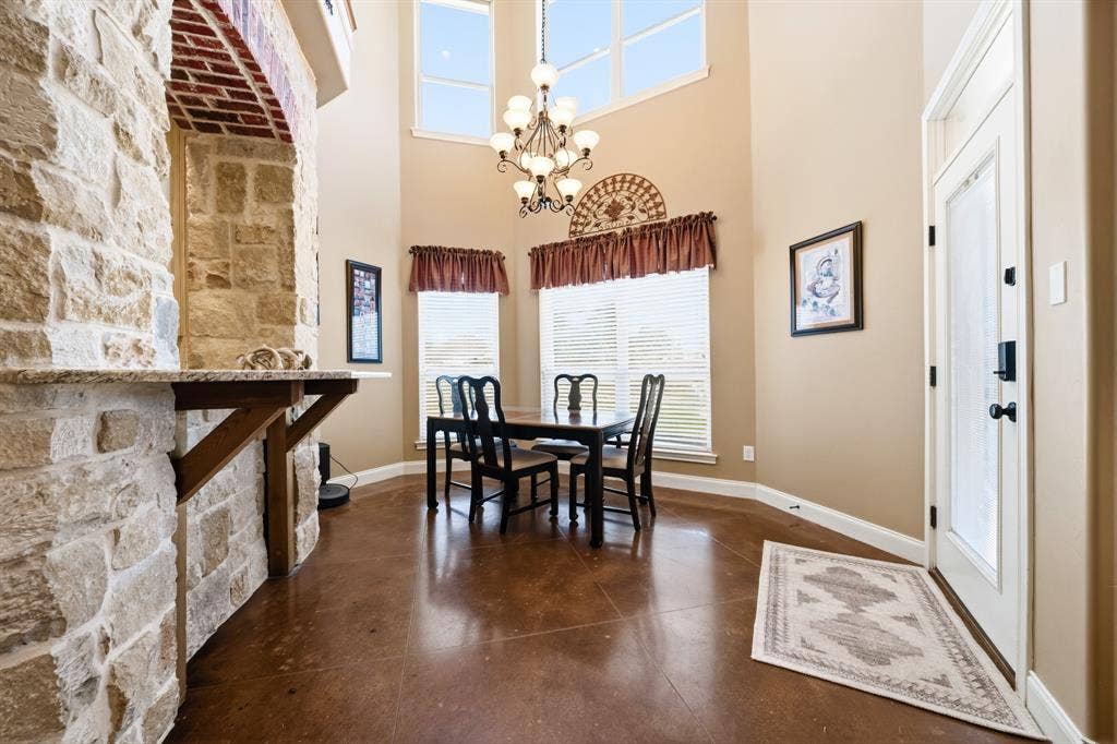 1021 Cascade Trail, McGregor, TX 76657 Stonework archway with a granite-finish countertop, high ceilings, large upper windows, and dark wood-finish flooring