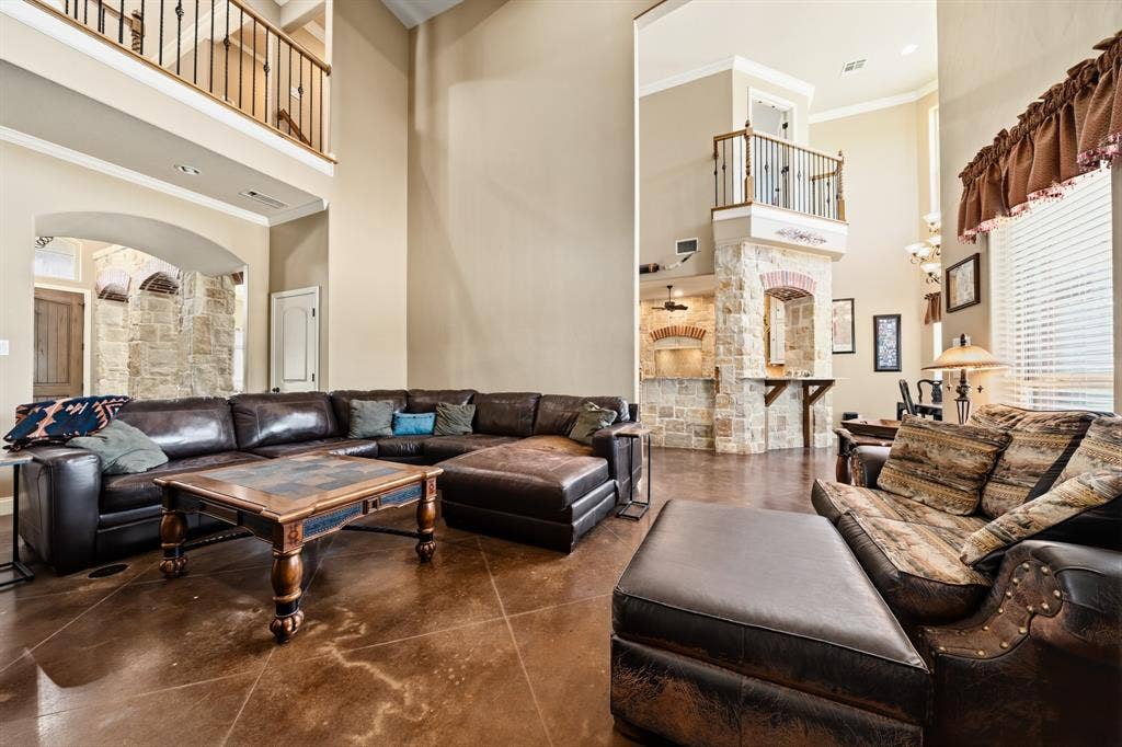1021 Cascade Trail, McGregor, TX 76657 Soaring ceilings, stone-clad architectural elements, and an upper-level balcony with metal balusters