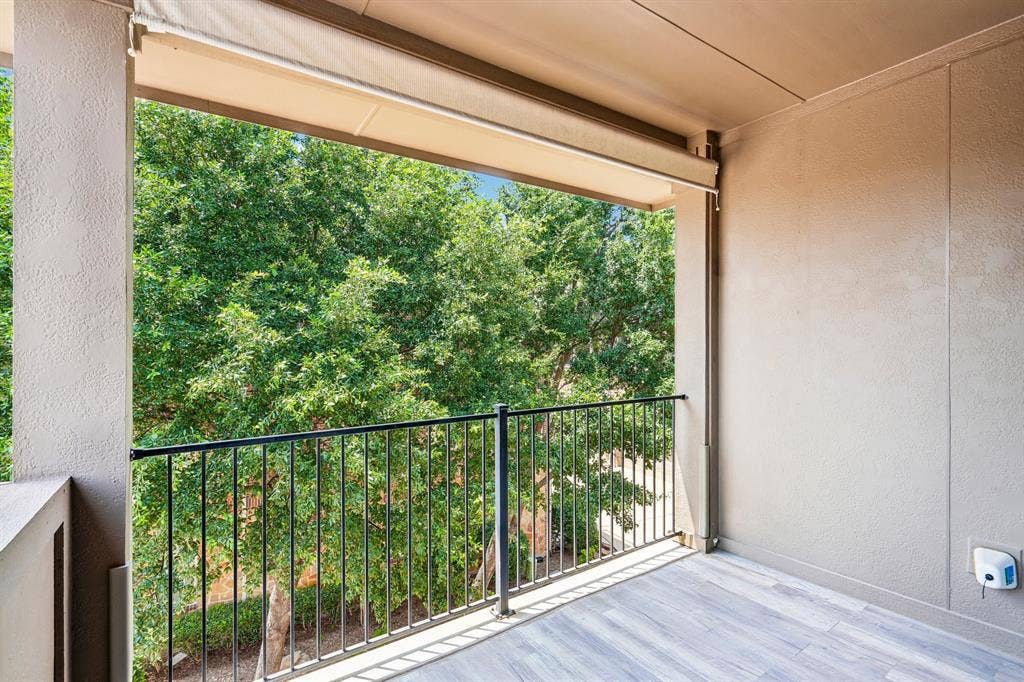 7937 Parkwood Boulevard, Plano, TX 75024 Outdoor balcony featuring wood-finish flooring, a black metal railing, and a retractable awning