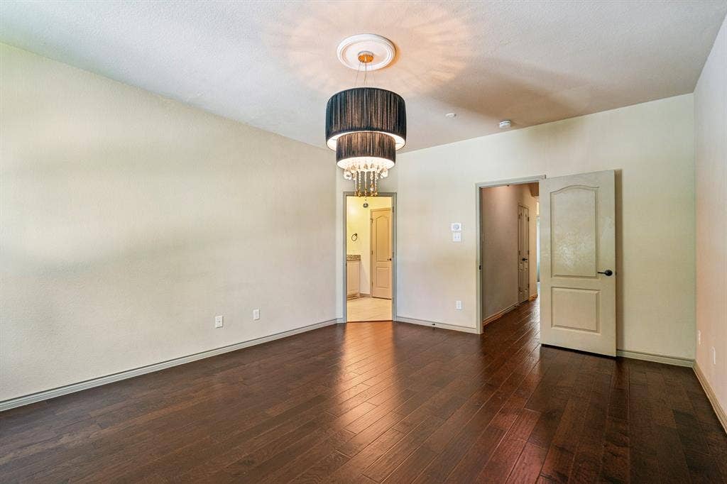 7937 Parkwood Boulevard, Plano, TX 75024 Dark wood-finish flooring, light neutral-toned walls, and a tiered chandelier with crystal accents