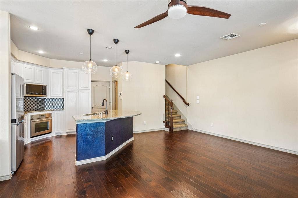 7937 Parkwood Boulevard, Plano, TX 75024 Kitchen featuring white cabinetry, stainless steel appliances, a checkered tile backsplash, and a central island with pendant lighting