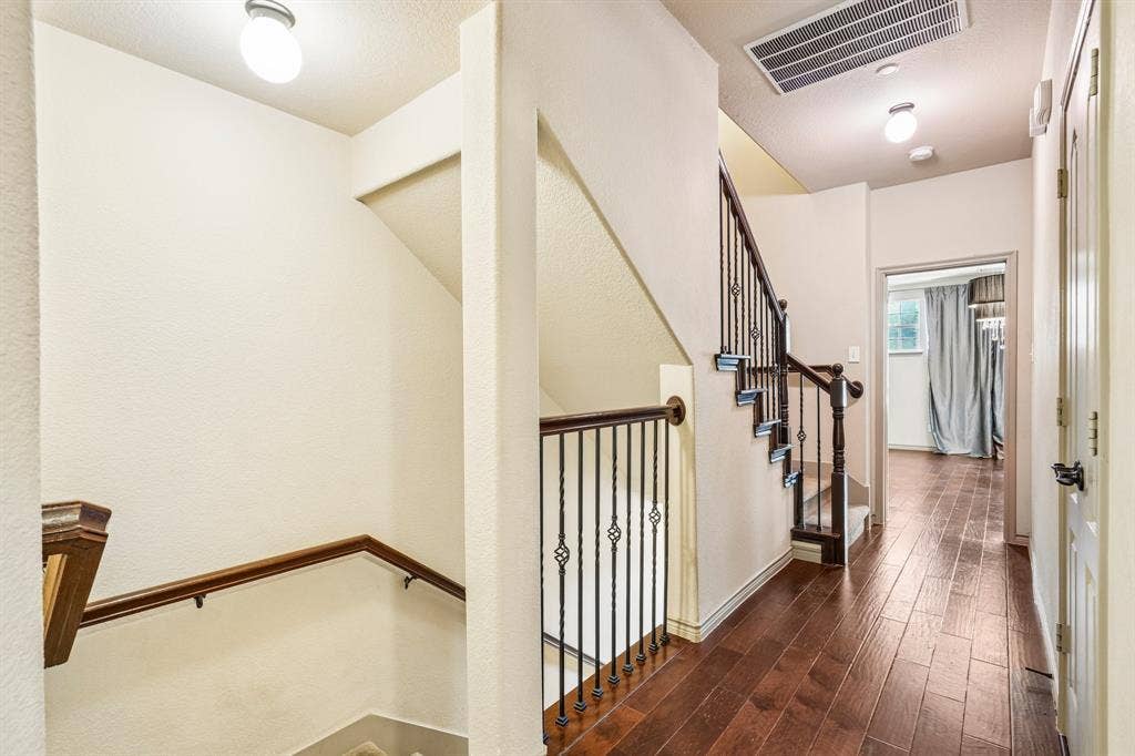 7937 Parkwood Boulevard, Plano, TX 75024 Hardwood-style flooring throughout the hallway and room, staircase with wrought iron balusters, and a rich wood-finish handrail