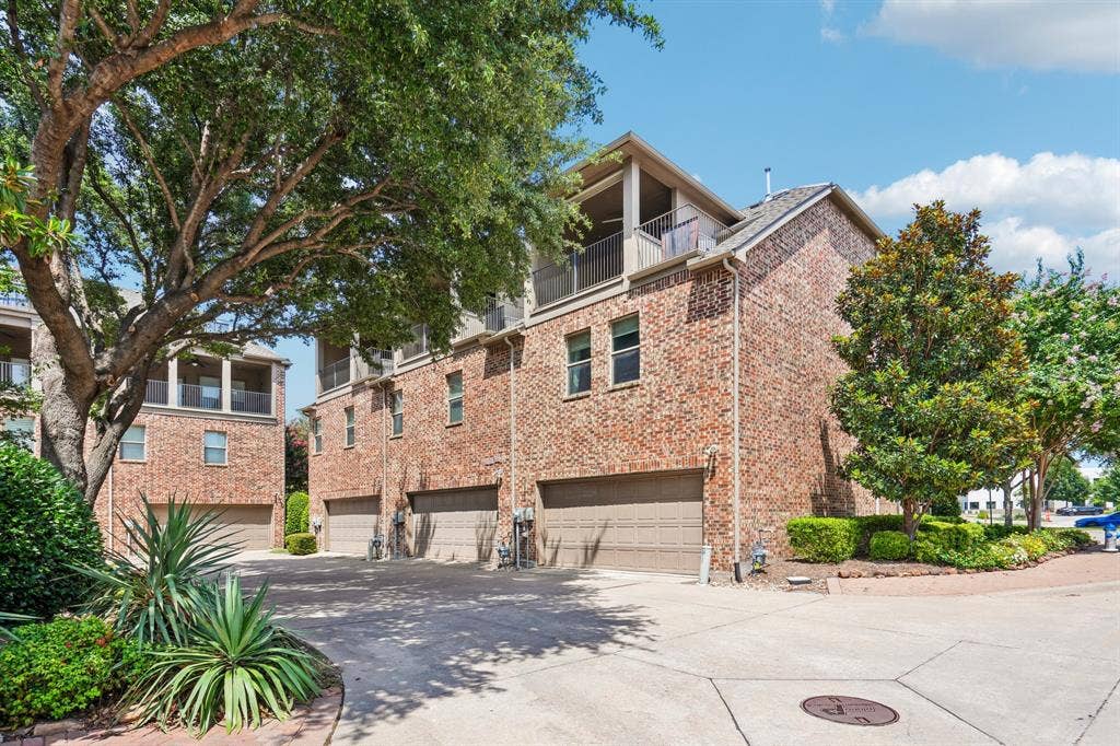 7937 Parkwood Boulevard, Plano, TX 75024 Brick exterior facade, multiple attached garages, upper-level balconies, mature trees, and landscaped shrubbery
