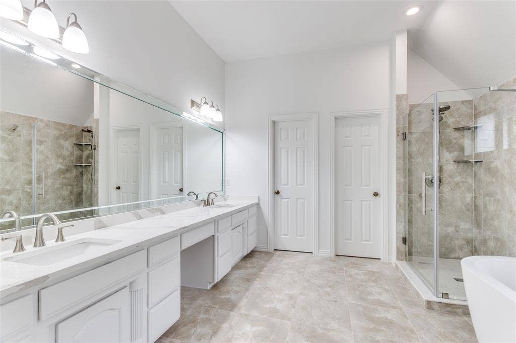 6315 Millwood Court, Arlington, TX 76016 Dual vanity with integrated sinks and brushed nickel faucets, expansive wall-mounted mirror, walk-in shower with glass enclosure, separate soaking tub, and tile flooring