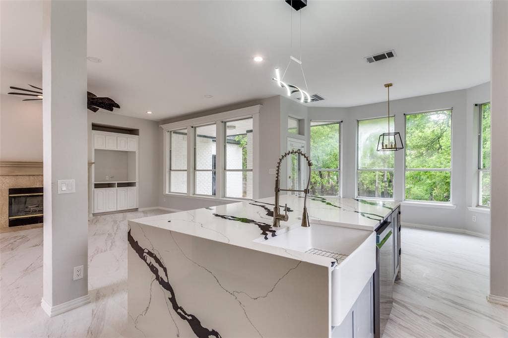 6315 Millwood Court, Arlington, TX 76016 Kitchen island with a farmhouse sink and modern faucet, under a contemporary linear light fixture