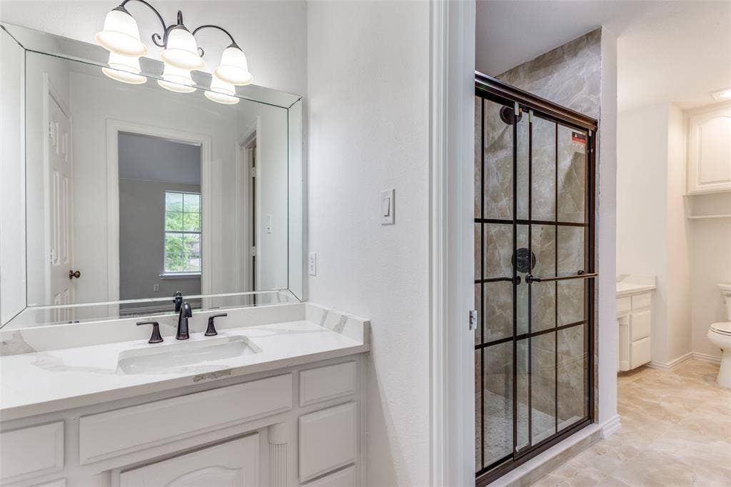 6315 Millwood Court, Arlington, TX 76016 White vanity with an integrated sink and bronze-finish faucet, framed mirror, and a bronze-finish light fixture