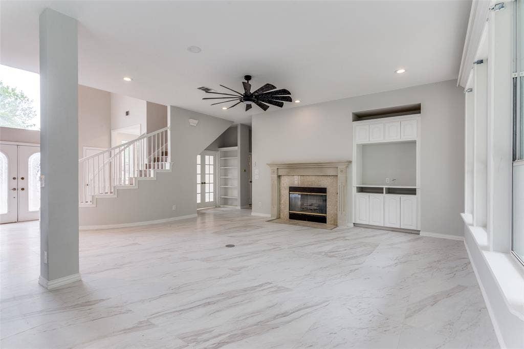 6315 Millwood Court, Arlington, TX 76016 Spacious living area featuring light-toned tile flooring, a built-in media cabinet, a stone fireplace, and a contemporary ceiling fan