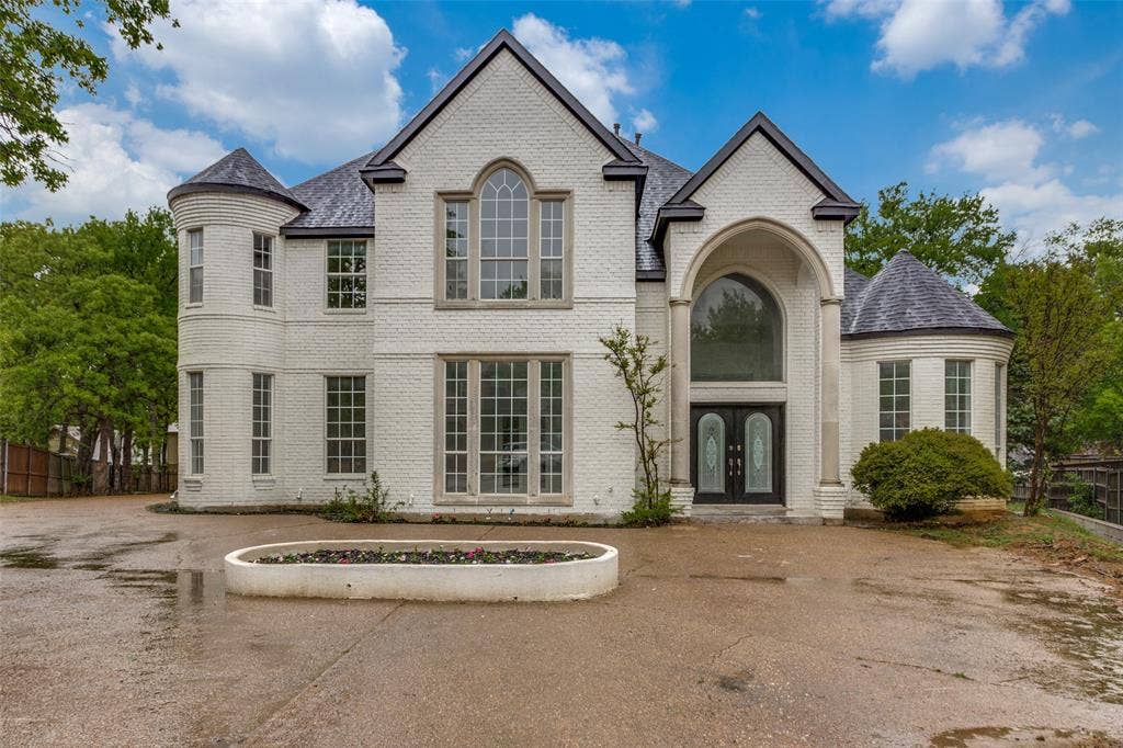 6315 Millwood Court, Arlington, TX 76016 White brick exterior with a prominent arched entry, dual turrets, and multiple multi-pane windows