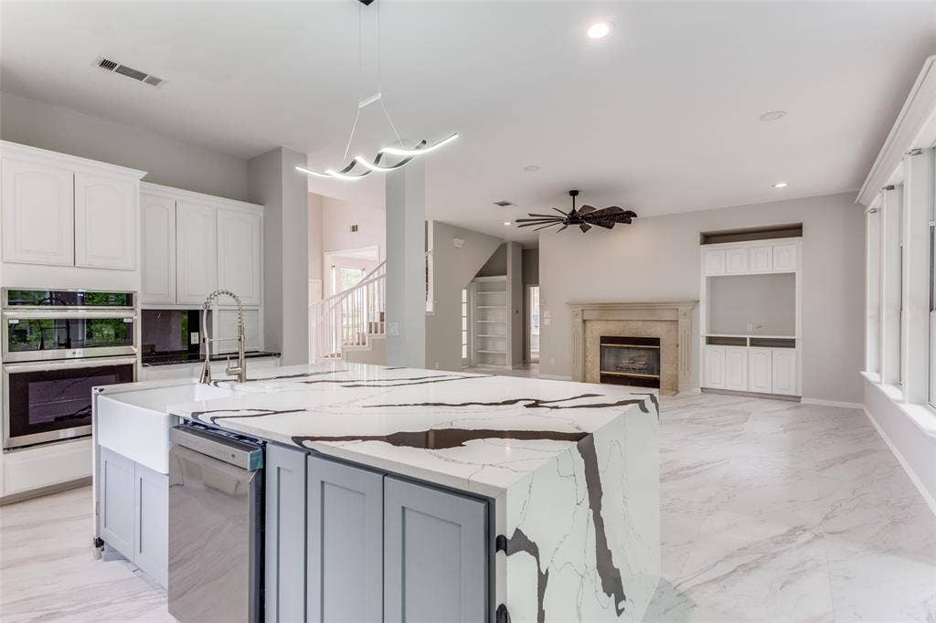 6315 Millwood Court, Arlington, TX 76016 Gourmet kitchen featuring a large island with waterfall countertop, built-in double ovens, farmhouse sink, and contemporary pendant lighting