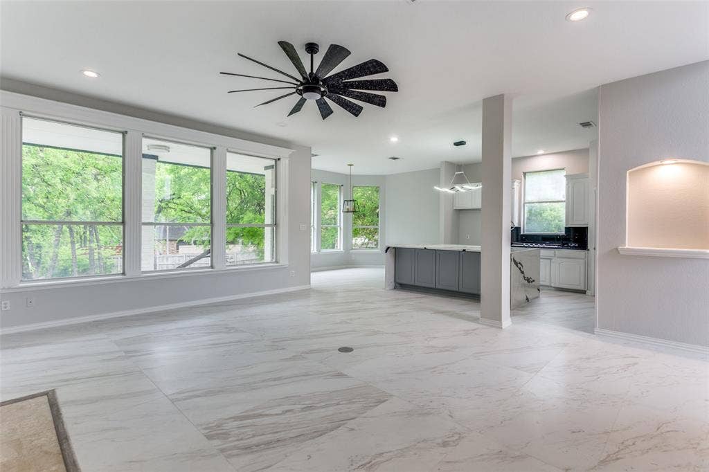 6315 Millwood Court, Arlington, TX 76016 Spacious open-concept living area featuring large windows, light-toned tile flooring, a modern black ceiling fan, and recessed lighting