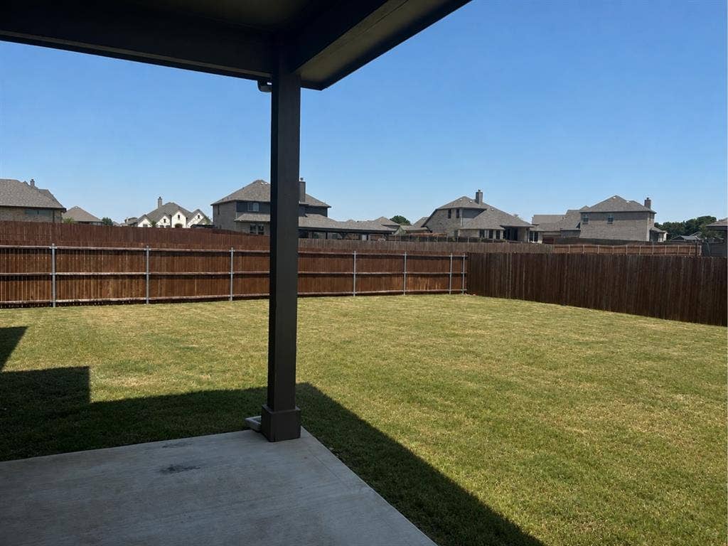 6002 14th Street, Midlothian, TX 76065 Expansive backyard featuring a manicured lawn, full privacy fencing, and a concrete patio with an overhead cover