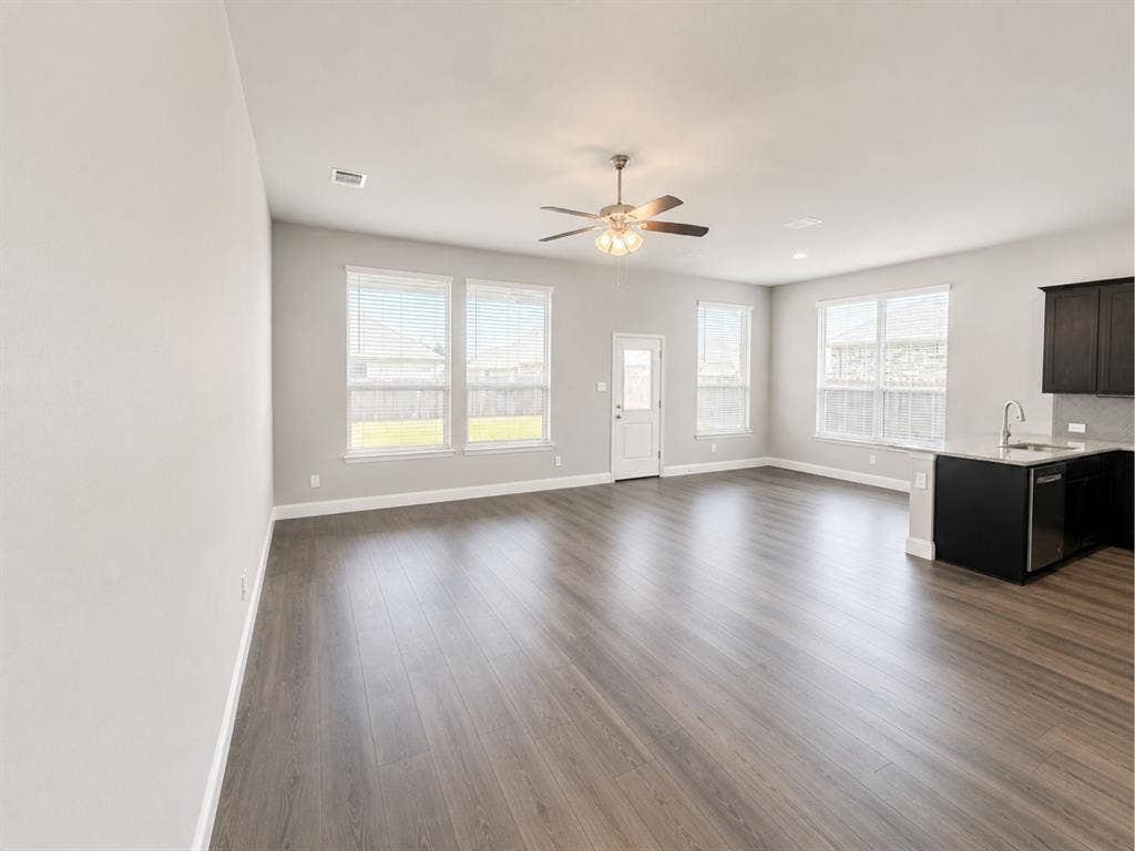 6002 14th Street, Midlothian, TX 76065 Open-concept living space featuring wood-finish flooring, multiple large windows, and a ceiling fan