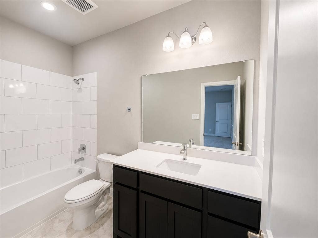 6002 14th Street, Midlothian, TX 76065 Spa-inspired primary bathroom featuring a double-sink vanity with black cabinetry, white quartz countertop, and polished chrome fixtures