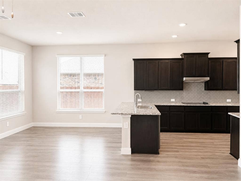 6002 14th Street, Midlothian, TX 76065 Kitchen featuring dark wood cabinetry, light granite countertops, stainless steel appliances, and a gray subway tile backsplash