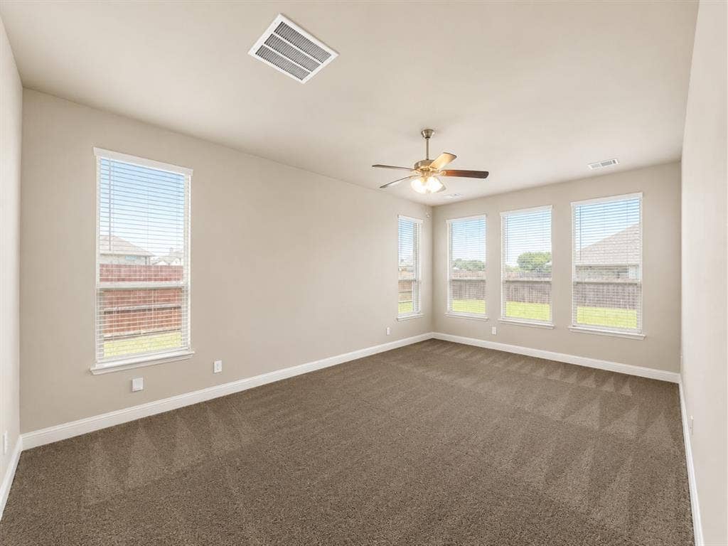 6002 14th Street, Midlothian, TX 76065 Spacious room featuring multiple windows, neutral wall tones, plush carpeting, a ceiling fan with integrated lighting, and white baseboards