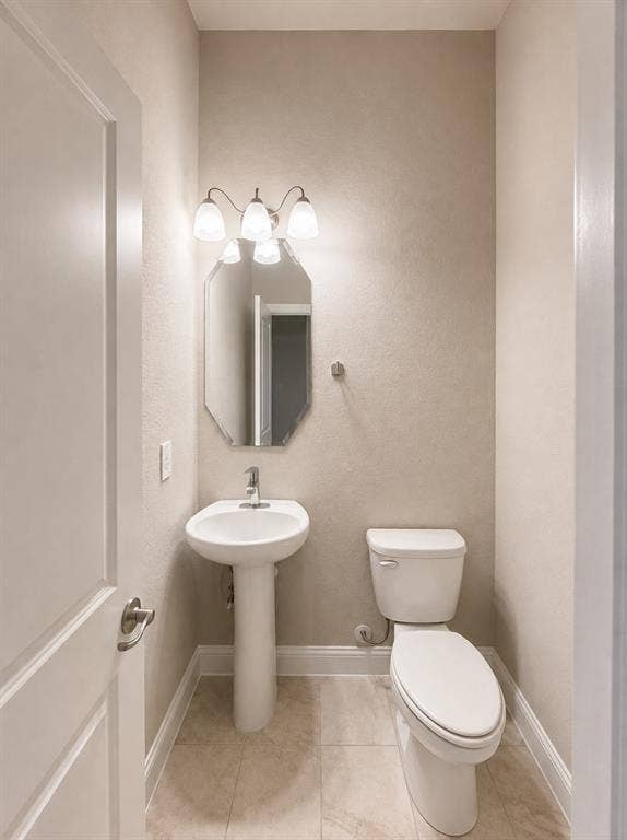 6002 14th Street, Midlothian, TX 76065 Powder room featuring a pedestal sink, a wall-mounted light fixture with three sconces, an octagonal mirror, a toilet, and light-toned floor tiling