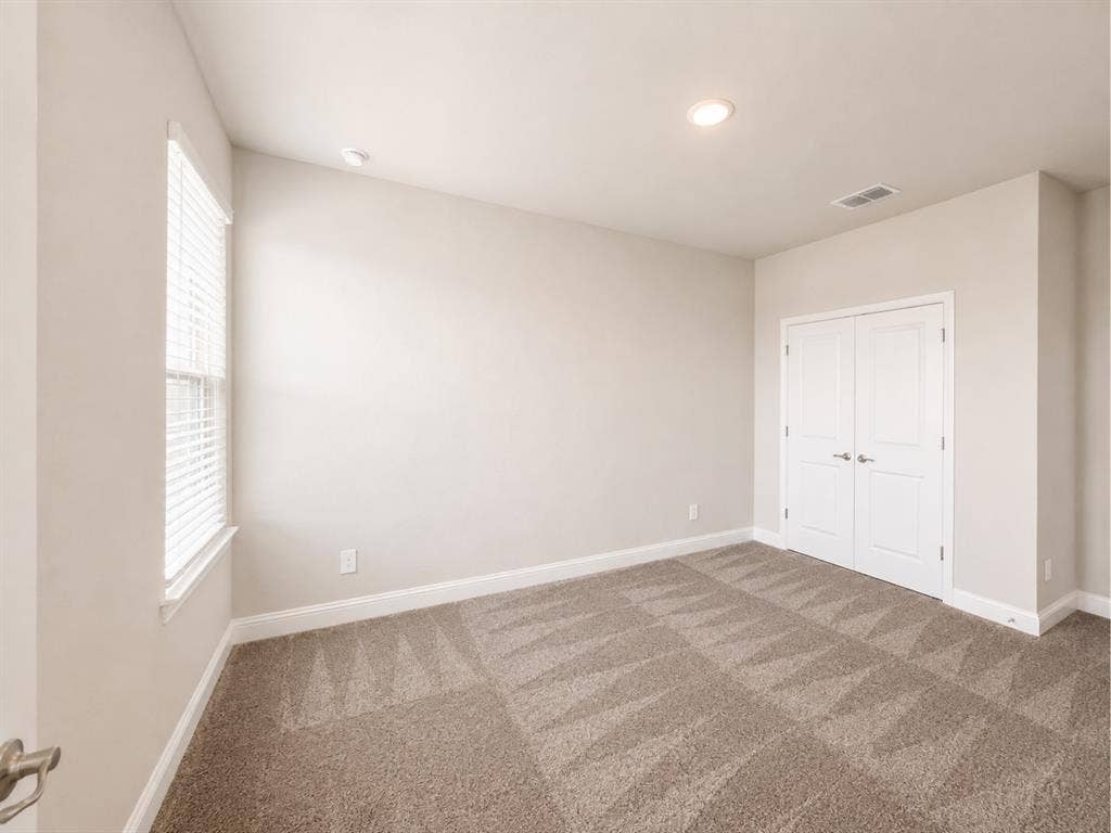 6002 14th Street, Midlothian, TX 76065 Bright bedroom featuring neutral wall finishes, recessed ceiling lighting, a large window with natural light, carpeting in neutral tones, and a double-door closet for ample storage