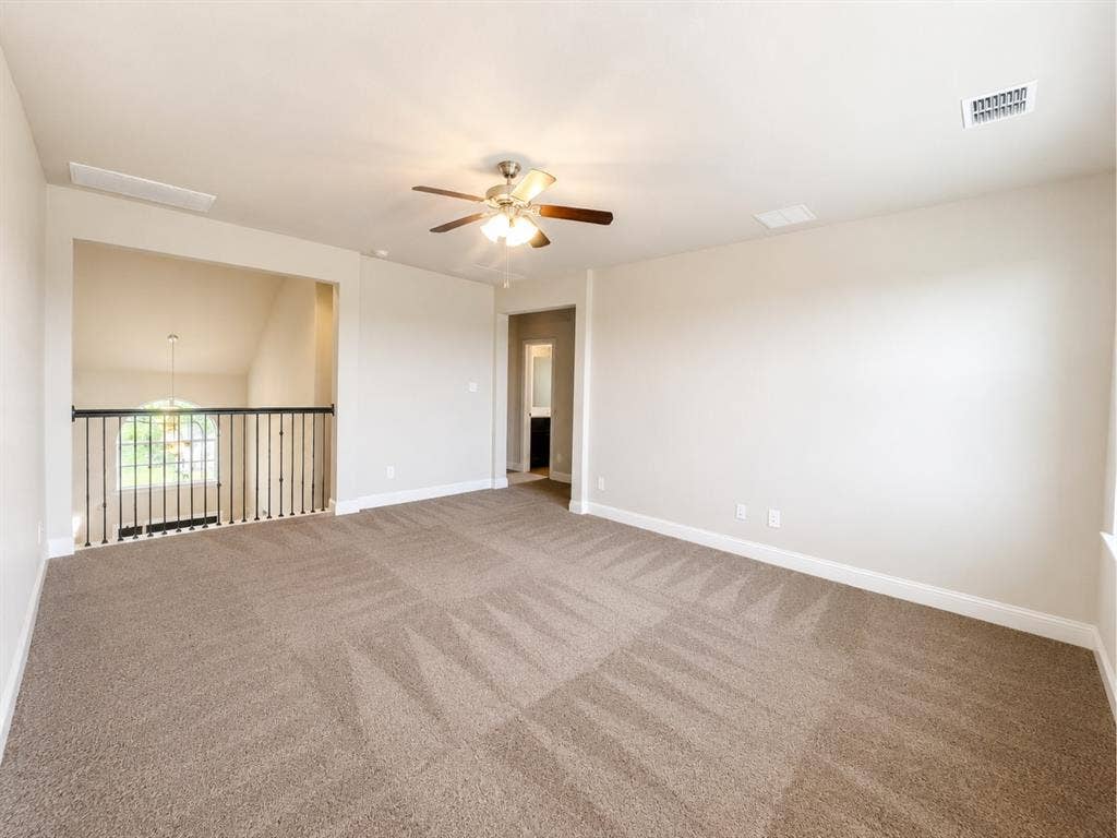 6002 14th Street, Midlothian, TX 76065 Spacious carpeted loft area featuring a ceiling fan, a railing overlooking a lower level, and ample wall space