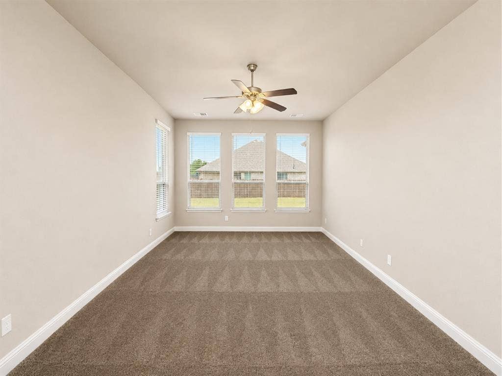6002 14th Street, Midlothian, TX 76065 Spacious room featuring vaulted ceilings, a ceiling fan with integrated lighting, and three tall windows with blinds