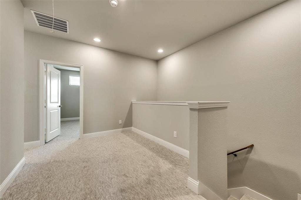 Loft area featuring neutral carpeting, recessed lighting, and a white balustrade
