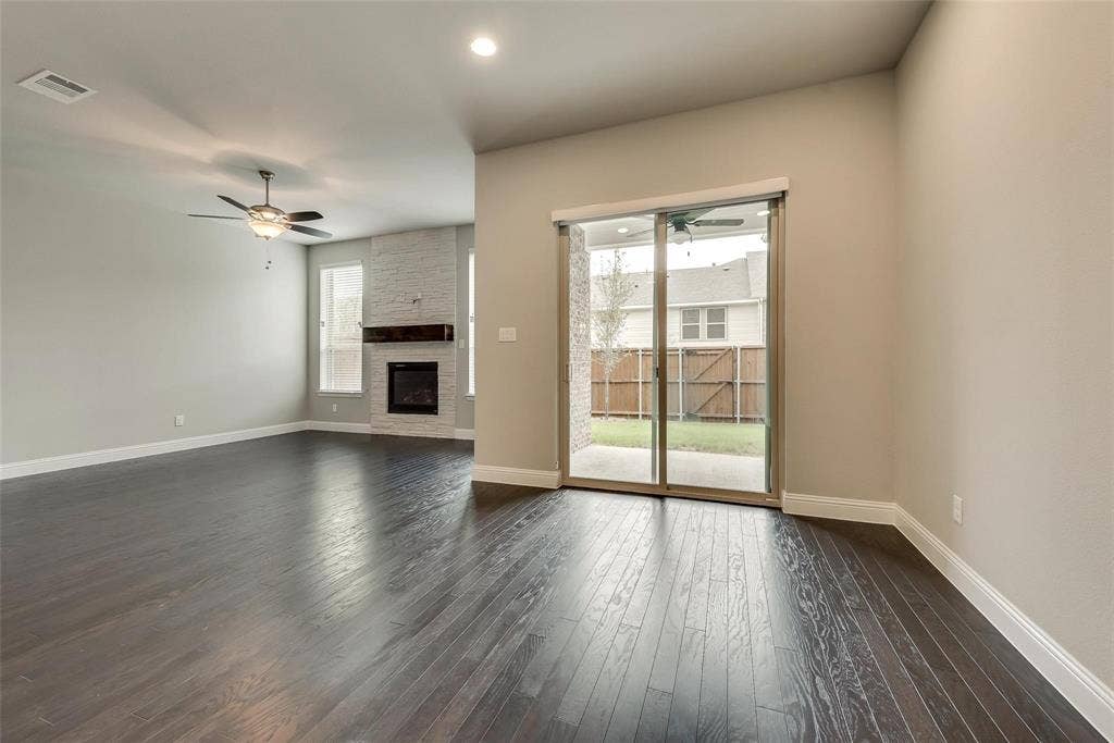 Wood-finish flooring throughout, featuring a stone-clad fireplace with a wood mantle, recessed lighting, and a ceiling fan