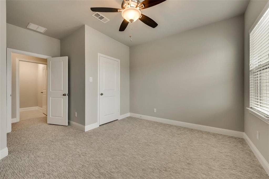 Plush patterned carpeting, ceiling fan with integrated lighting, window with horizontal blinds, and paneled interior doors