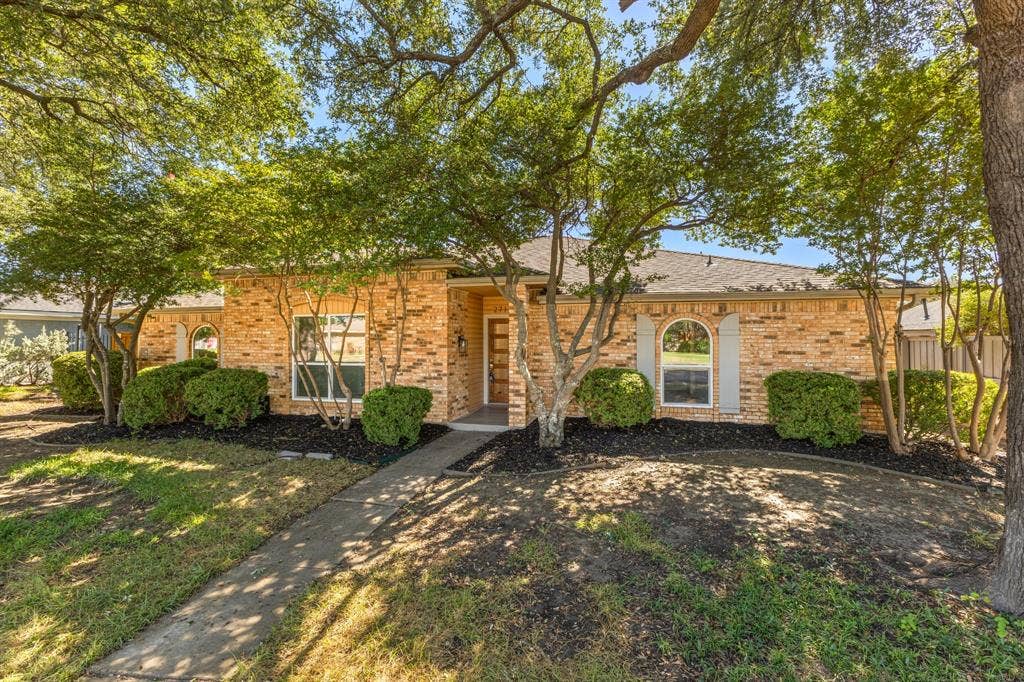 2716 Landershire Lane, Plano, TX 75023 Brick exterior featuring an arched window, a covered entryway, and mature landscaping