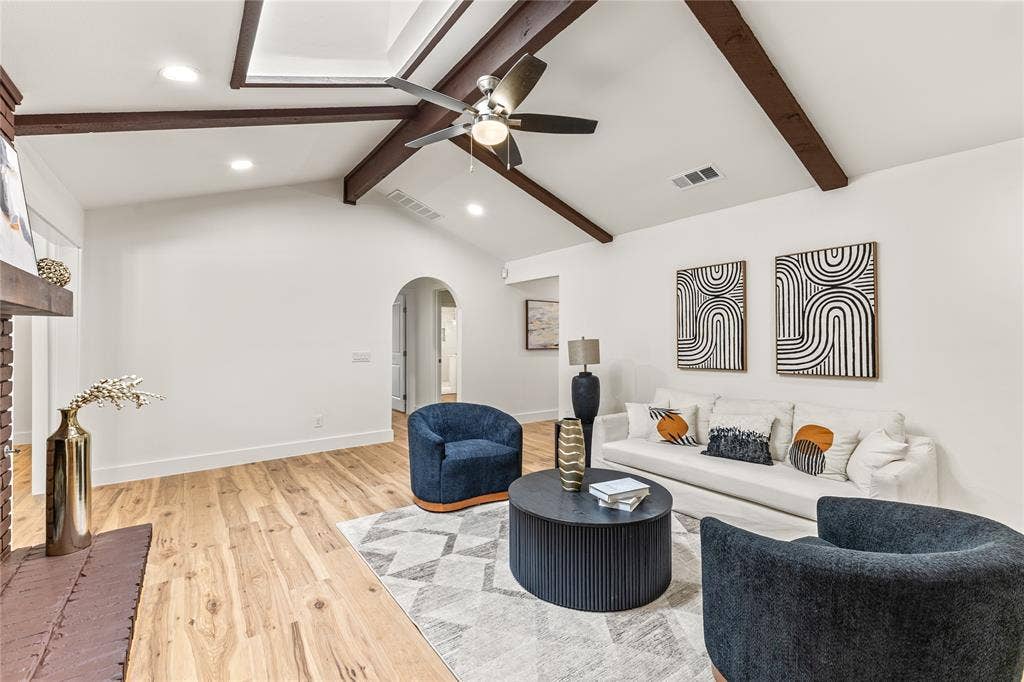 2716 Landershire Lane, Plano, TX 75023 Vaulted ceiling with exposed wood beams, wood-finish flooring, brick fireplace, recessed lighting, and an arched doorway