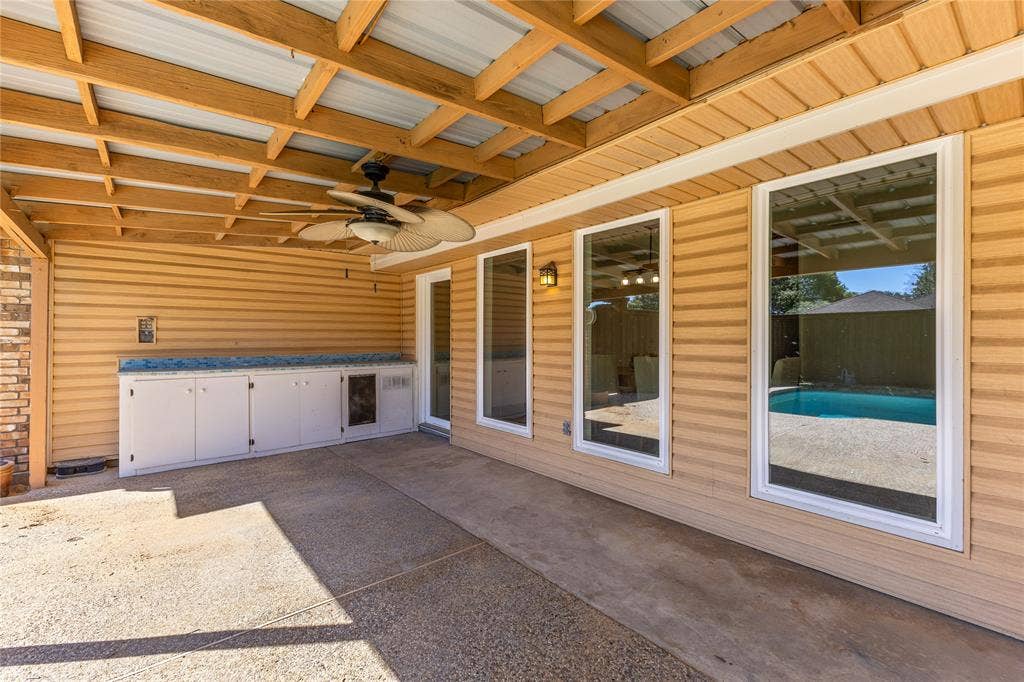 2716 Landershire Lane, Plano, TX 75023 Covered patio with exposed wood beam ceiling, ceiling fan with integrated lighting, built-in cabinetry with counter space, and three large windows