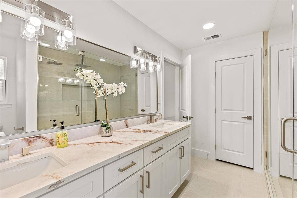 2716 Landershire Lane, Plano, TX 75023 Double vanity with undermount sinks, stone countertops, and brushed nickel fixtures