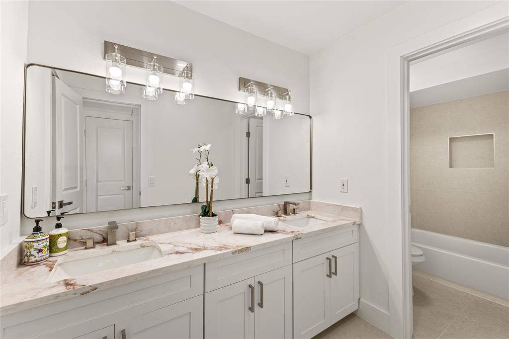 2716 Landershire Lane, Plano, TX 75023 Dual vanity with stone countertop, white shaker cabinetry, rectangular undermount sinks, and brushed nickel fixtures
