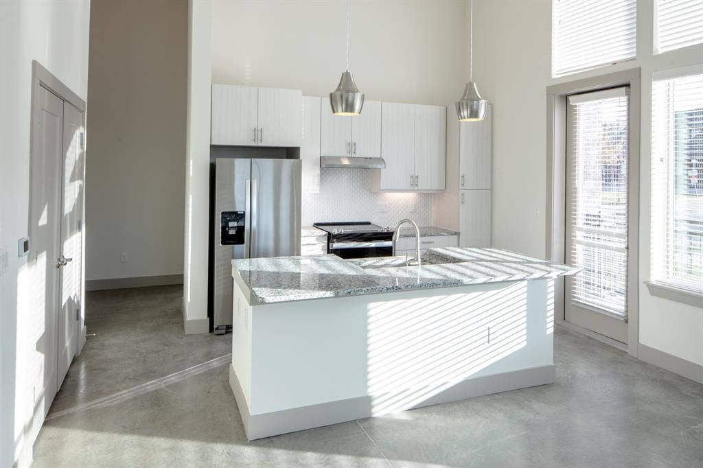 601 N Oak Street, #118, Roanoke, TX 76262 Kitchen featuring white cabinets, hanging light fixtures, tasteful backsplash, stainless steel appliances, and a high ceiling