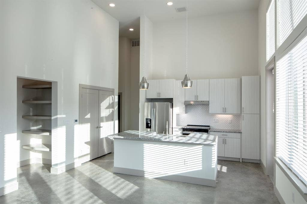 601 N Oak Street, #118, Roanoke, TX 76262 Kitchen with appliances with stainless steel finishes, a kitchen island with sink, a towering ceiling, and a wealth of natural light