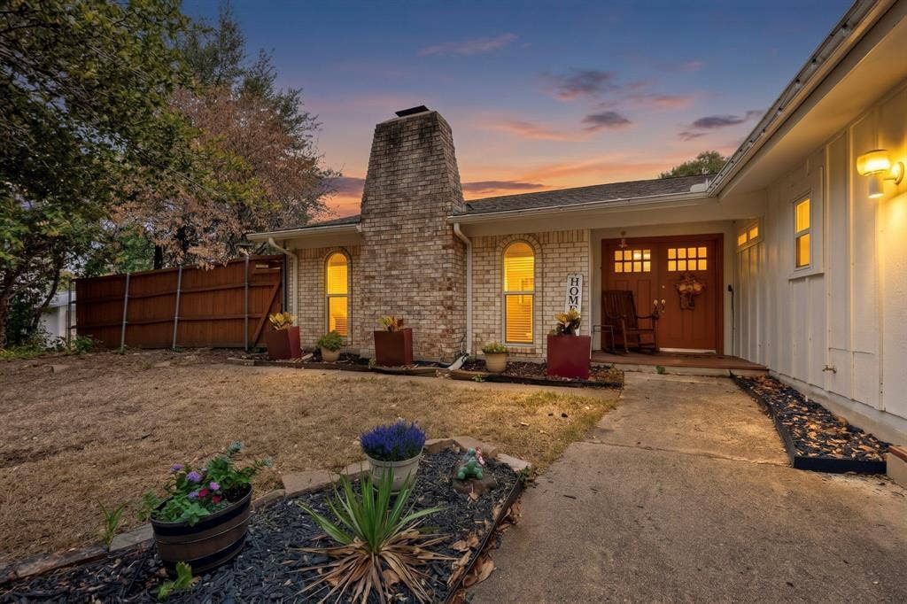 1418 Stony Brook Lane, Garland, TX 75043 Brick exterior with a prominent chimney, arched windows, covered entry, and wood front doors