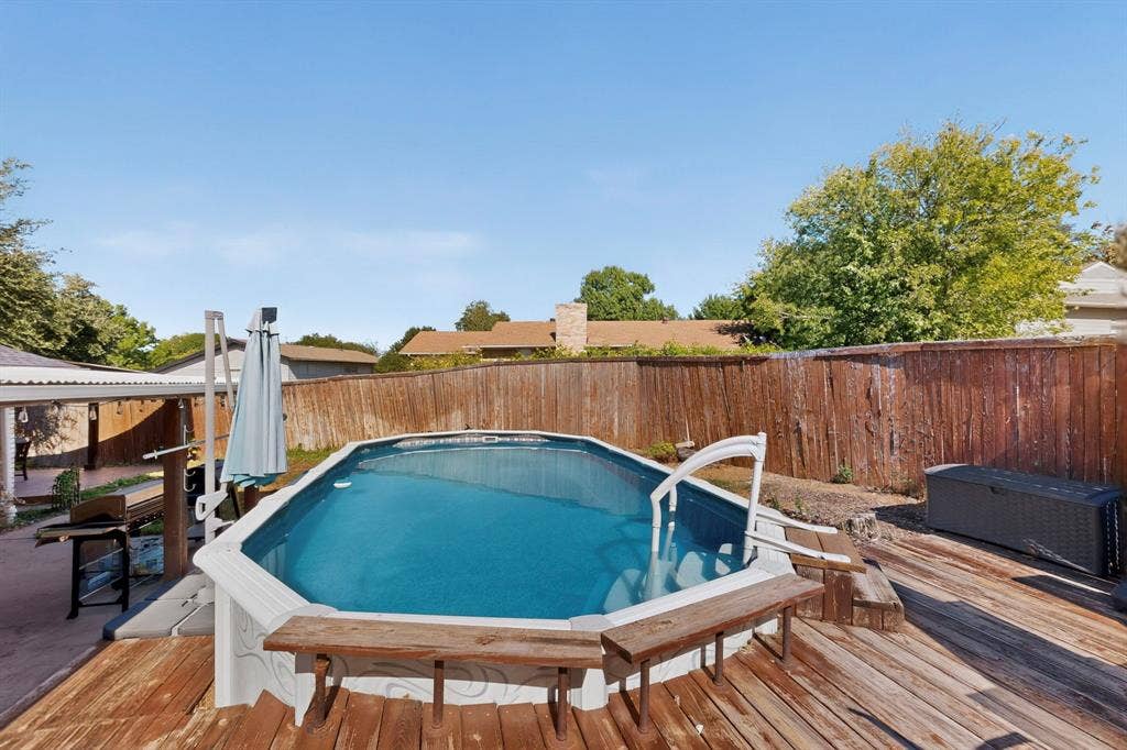 1418 Stony Brook Lane, Garland, TX 75043 Backyard featuring an above-ground pool with a surrounding wood-finish deck and privacy fencing