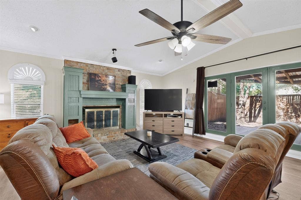 1418 Stony Brook Lane, Garland, TX 75043 Vaulted ceilings, wood-finish flooring, stone-faced fireplace with a decorative mantel, ceiling fan, and sliding glass doors