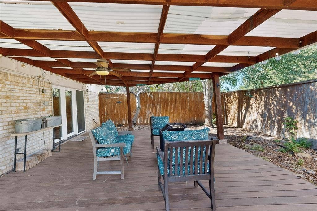 1418 Stony Brook Lane, Garland, TX 75043 Expansive outdoor deck with wood-finish flooring, a covered pergola, and a ceiling fan