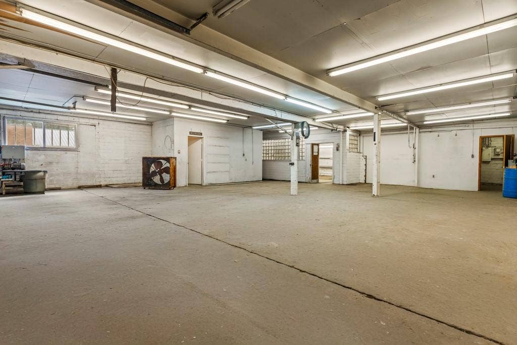 414 E Marshall Street, Gilmer, TX 75644 Expansive open space with concrete flooring, exposed overhead fluorescent lighting, and multiple structural support pillars